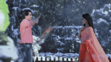 a man and a woman are standing in the rain looking at each other