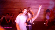 a man and a woman are posing for a picture at a basement party .