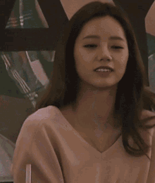 a woman in a pink sweater looks at the camera with a straw in her hand