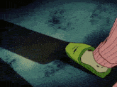 a person wearing a pink sweater and green slippers is holding a large saw