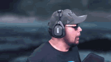 a man wearing headphones and a hat has the letter s on his cap
