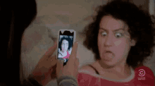 a woman taking a picture of herself with a cell phone