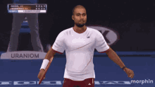a tennis player is holding a racquet in front of a sign that says uranium