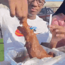 a man wearing glasses is eating a large piece of fried meat .