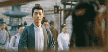 a man in a kimono is standing in front of a group of people in a crowd .