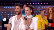 a man holding a microphone stands next to a woman in a white dress