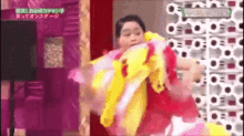 a woman in a red and yellow dress is dancing in front of a wall .
