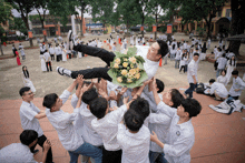 a man is being thrown in the air with a bouquet of flowers on his shoulder