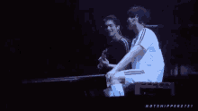 a man in a white shirt is sitting next to another man in a black shirt ..