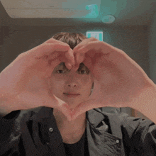 a man making a heart shape with his hands in front of his face