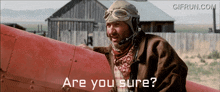 a man wearing a helmet and goggles is sitting on a red plane and says " are you sure "
