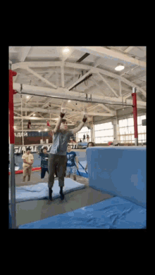 a man is jumping over a blue mat in a gym with a sign that says ' army ' on it