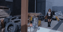 a woman in a crop top stands in a warehouse surrounded by tires and other items