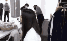 a woman is sitting at a table in a room with a group of people .