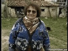 an older woman wearing sunglasses and a scarf is standing in front of a stone building with the url freegifmaker.me visible