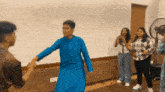 a group of people are dancing in a room with a fan behind them