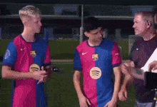 two soccer players are standing next to each other on a field with a man standing behind them .