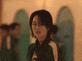 a woman with short hair is wearing a green jacket with the letter o on it