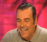 a man in a sweater is smiling with his eyes closed .