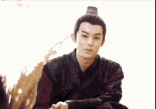 a man with a bun on his head is wearing a black vest and a red shirt