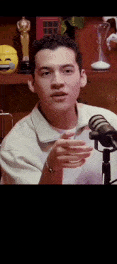 a man speaking into a microphone in front of a shelf with oscar statues