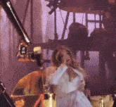 a woman in a white dress singing into a microphone on a stage