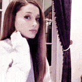 a woman is taking a selfie in front of a window with purple curtains