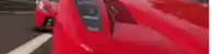 a close up of a red car driving down a street .