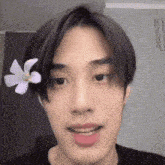 a young man with a flower in his hair is making a funny face .