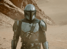 a man wearing a helmet and armor is walking through the desert