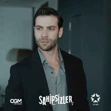a man in a suit is standing in front of a sign that says sahipsizler