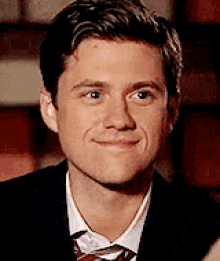 a young man in a suit and tie is smiling .