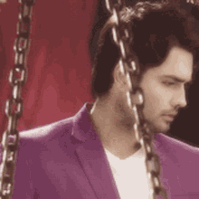 a man in a purple jacket is chained to a swing .