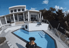 a man stands in front of a swimming pool in front of a house