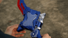 a man in a suit is holding a blue and red toy weapon