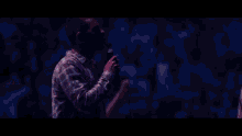 a man singing into a microphone with a guitar in front of him