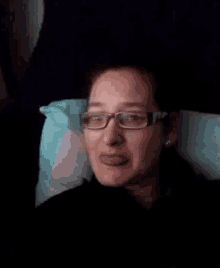 a woman wearing glasses laying on a pillow