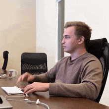 a man sits at a desk in front of a mug that says also