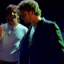 two men are standing next to each other in a dark room and one is giving the middle finger