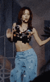 a woman in a black top and blue pants is dancing on a stage
