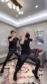 two men are dancing in a living room with a couch .