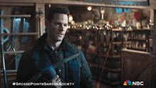 a man holding a pair of scissors in a store with nbc on the bottom
