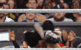 a wrestling match is being held in front of a crowd of people .
