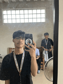 a man taking a selfie in front of a mirror with a lanyard around his neck that says ytb university