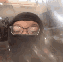 a person wearing glasses and a black mask looks at the camera