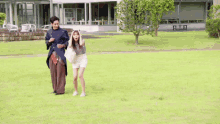 a man and a woman are walking through a grassy field .