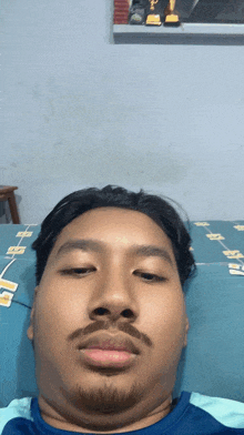 a man with a beard is laying on a bed and looking at the camera