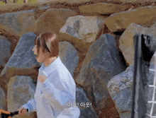 a woman standing in front of a wall of rocks with korean writing