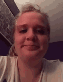 a close up of a woman 's face with a purple wall in the background .