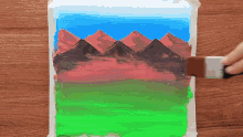 a person is painting a picture of a mountain range